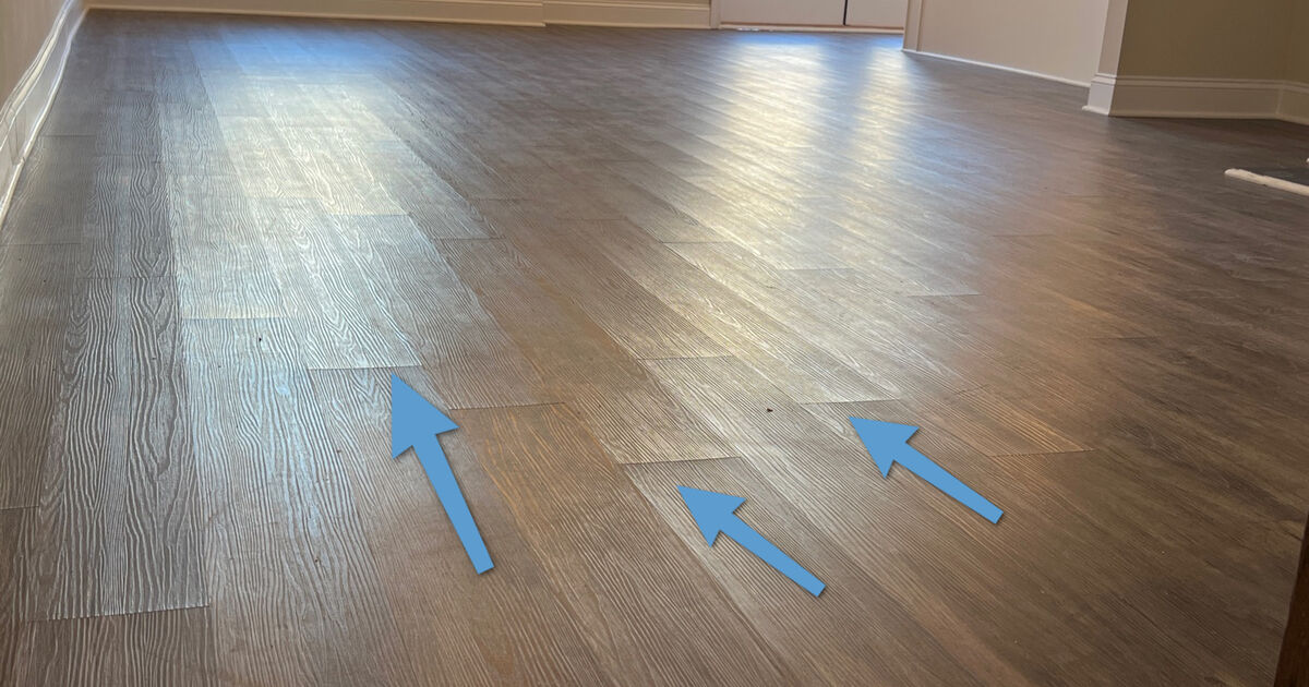 Refinished floor with inspection arrows marking defects from unpermitted renovation work